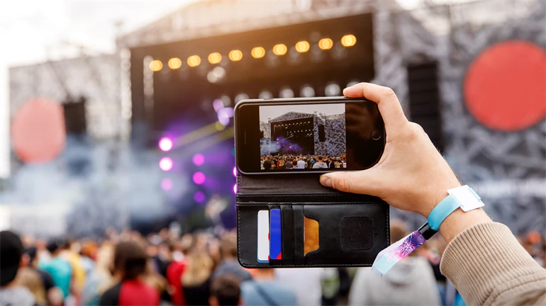 person spelar in konsert med mobilen, utomhusscen