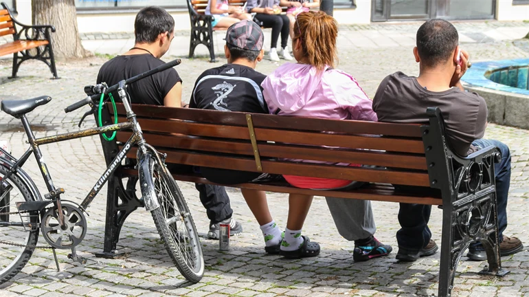 Fyra ungdomar på en parkbänk på ett torg