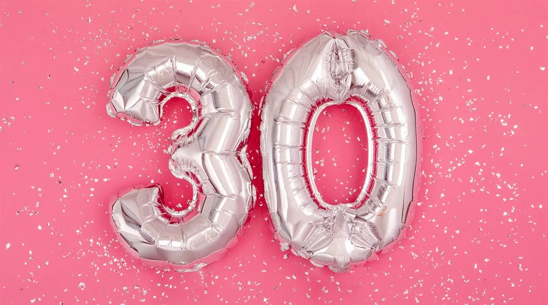 Silverfärgade ballonger i formen 3 och 0 mot en rosa bakgrund med silverglitter på.