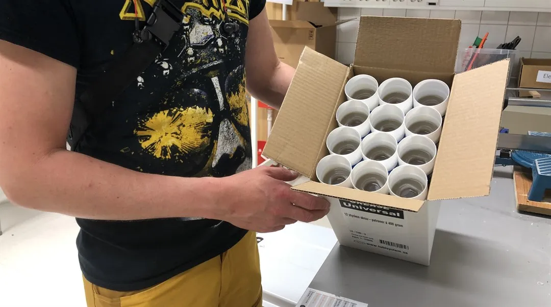 Person håller i kartong innehållande ett flertal fettpatroner