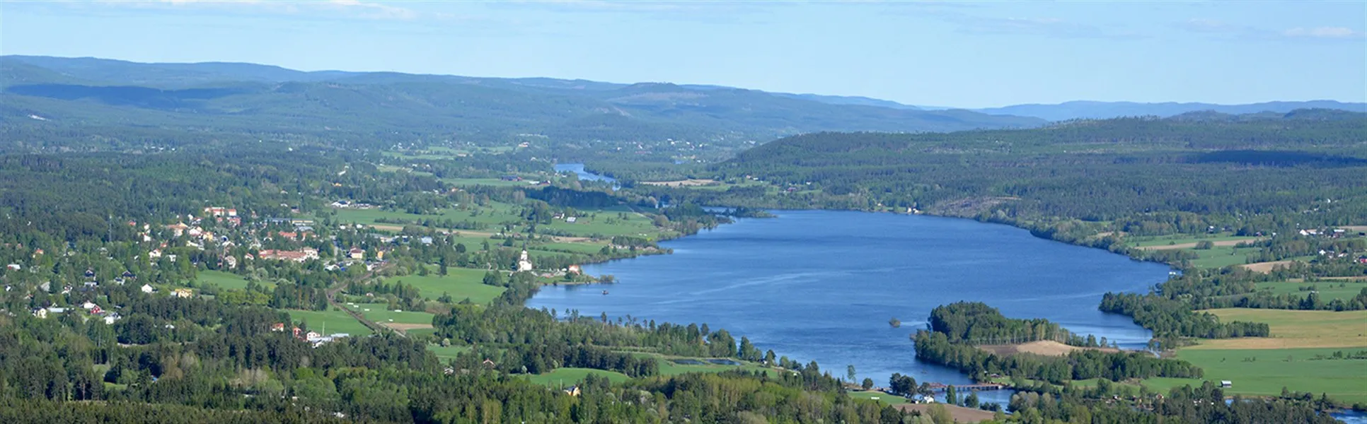 Landskapsbild med gröna berg, ängar och en sjö