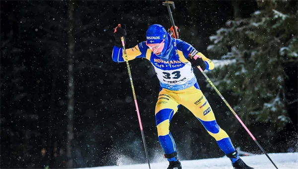 Skidskytt i svensk landslagsdress och med gevär på ryggen