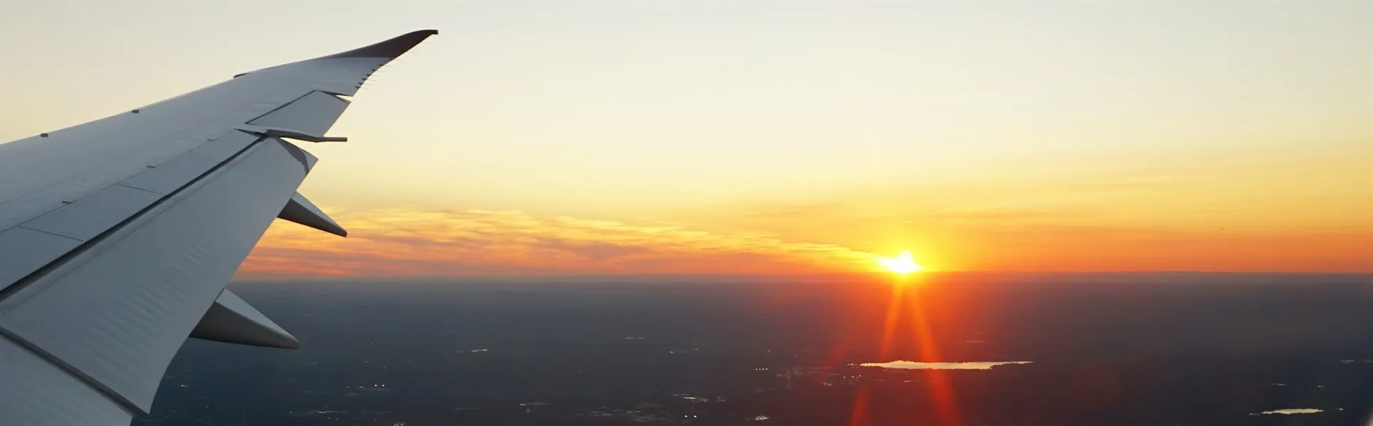 Airplane wing and sunset through an airplane window