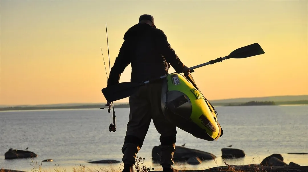 person bär kajak i solnedgång vid strand