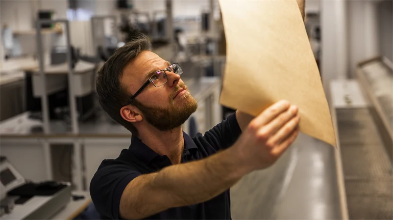 Kille som håller papper mot en lampa