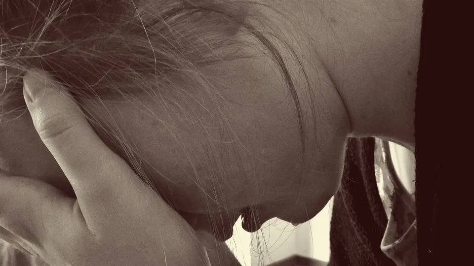 A woman hides her face in her hand and looks like she's crying.