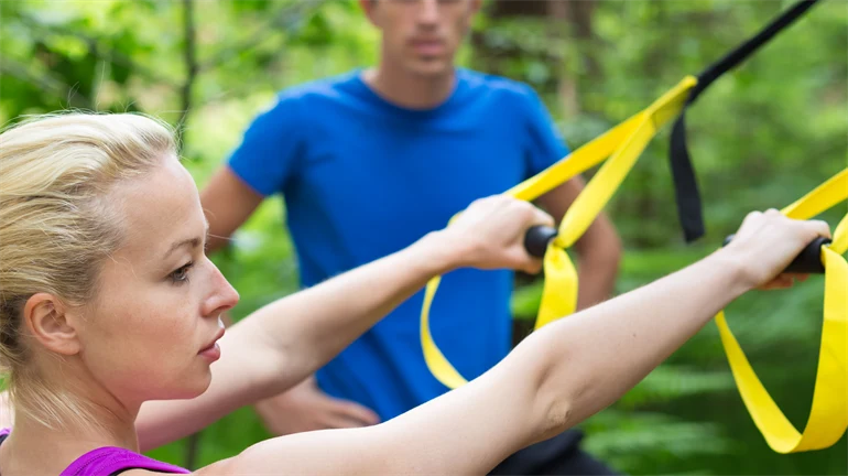 Kvinna och man tränar på ett utegym i naturen