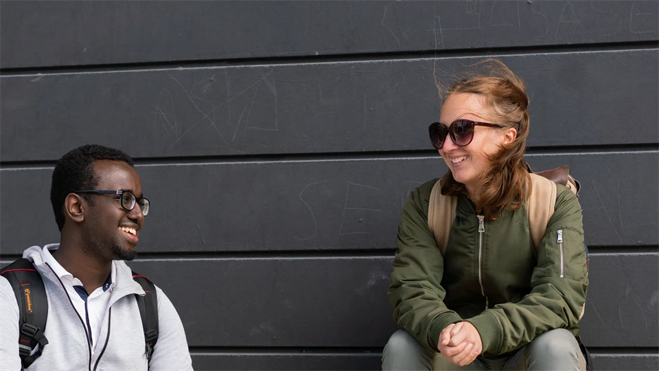 Two students sitting on a yellow bench.