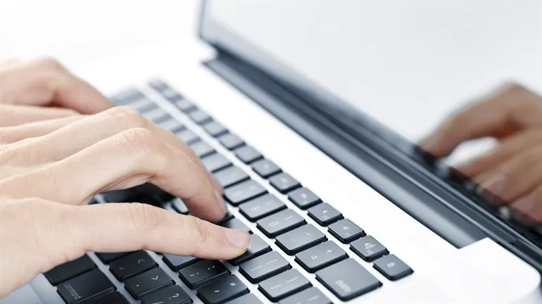 Hands typing on laptop keyboard